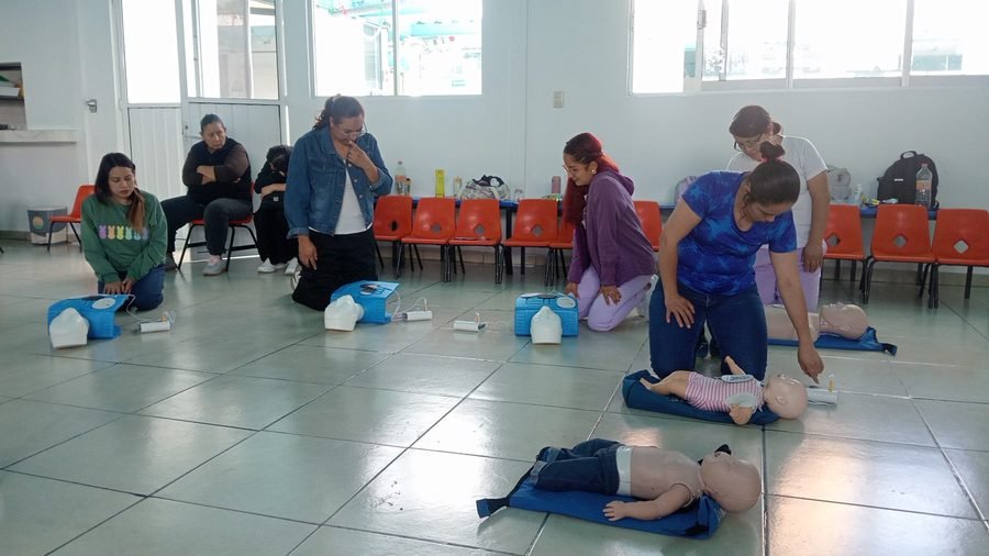 Grupo de personas practicando RCP en maniquíes infantiles