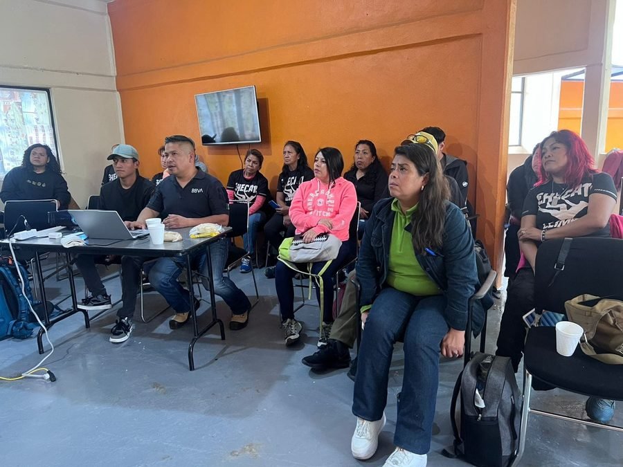 Grupo numeroso de personas sentadas en un salón durante una sesión de capacitación en protección civil