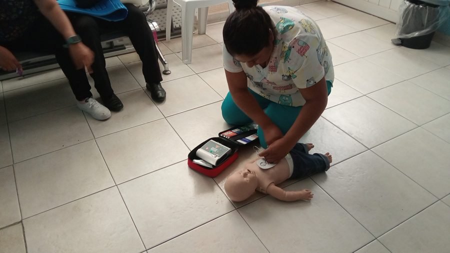 Persona practicando RCP y uso de DEA en maniquí infantil