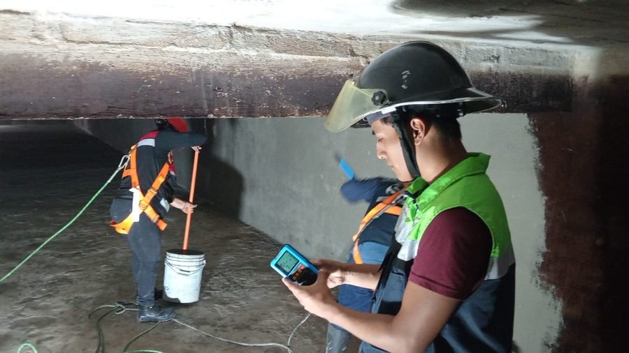Personal con arnés y medidor de gases en un espacio confinado