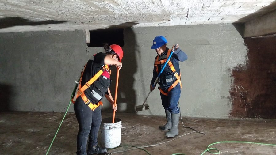 Dos personas con arnés de seguridad trabajando en un espacio confinado tipo túnel